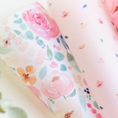 Rolos de papel decorativo com padrão floral aquarelado em tons suaves