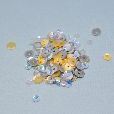 Lantejoulas sortidas em várias formas e cores numa superfície azul