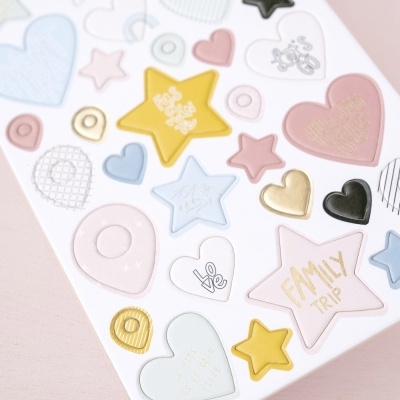 Folha de autocolantes coloridos em formas de corações, estrelas e círculos sobre fundo rosa