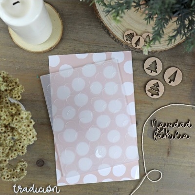 Cartão decorativo com padrão de bolinhas, objetos de Natal em madeira e vela sobre mesa