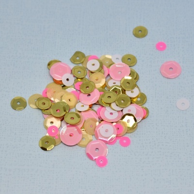 Lantejoulas coloridas rosa, dourado e branco sobre fundo azul claro