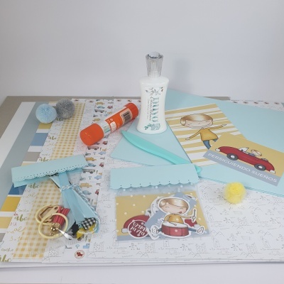 Materiais de artesanato e papelaria com cola UHU, pompons e papéis coloridos com desenhos de crianças.