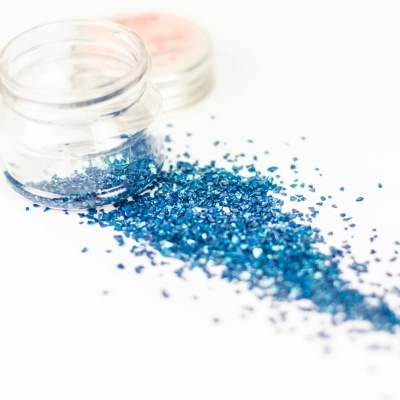 Frasco de glitter azul aberto sobre fundo branco