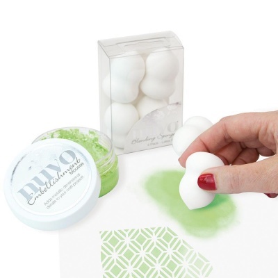 Esponja branca para maquilhagem e recipiente de creme com tampa branca ao lado