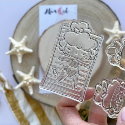 Carimbo transparente com desenho de personagem deitada numa toalha às riscas