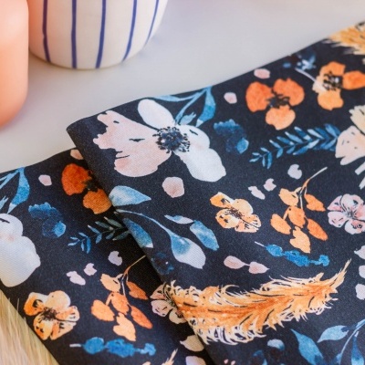 tecidos com padrão floral colorido sobre fundo preto junto a vasos decorativos