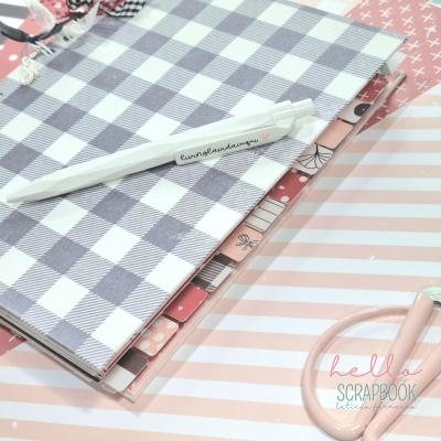 Dois cadernos decorativos, caneta branca com texto, tesoura rosa clara e texto 'hello SCRAPBOOK'