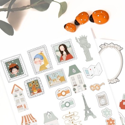 Folha de autocolantes variados e três joaninhas decorativas sobre superfície branca