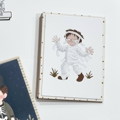 Cartaz infantil de criança fantasiada de múmia em parede branca