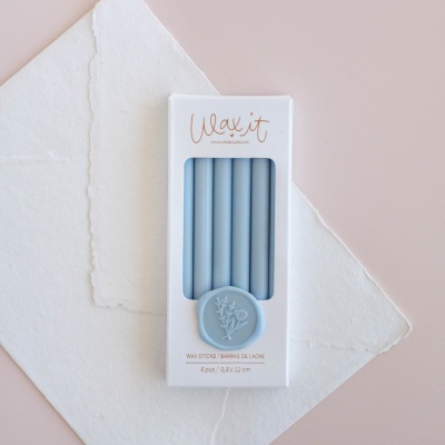 Conjunto de varetas de cera azul claro em caixa branca com selo de cera azul
