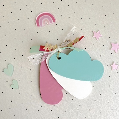 Etiquetas coloridas em forma de nuvem e gota com laço, sobre fundo branco com pontos pretos e pequenos adornos coloridos