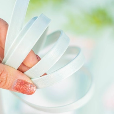 Mão segura pulseiras brancas lisas em fundo desfocado verde e branco