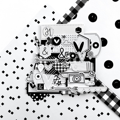 Recortes de papel em preto e branco com vários padrões decorativos sobre fundo preto e branco.