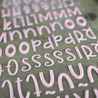 Letras e símbolos em relevo cor-de-rosa sobre uma superfície verde clara