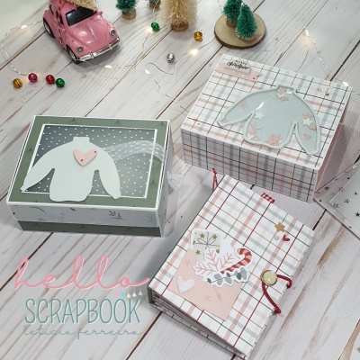 Três caixas decorativas de Natal com padrões e motivos festivos em mesa clara