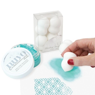 Esponjas brancas de maquilhagem, pigmento mineral azul turquesa em pó e aplicação sobre papel branco com padrão geométrico azul.