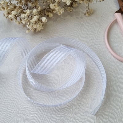 Fita decorativa branca translúcida com riscas e flores secas ao fundo