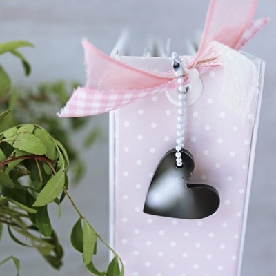 Caixa rosa com bolinhas brancas, laço de fita rosa e branco e pingente de coração metálico