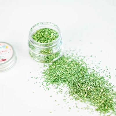 Frasco aberto de glitter verde com tampa ao lado sobre fundo branco