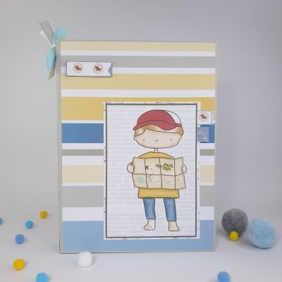 Caderno decorado com menino e mapa, riscas horizontais coloridas e pompons no entorno.