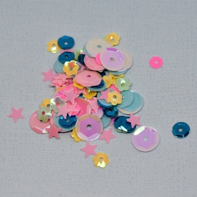 Lantejoulas coloridas em várias formas sobre superfície cinza