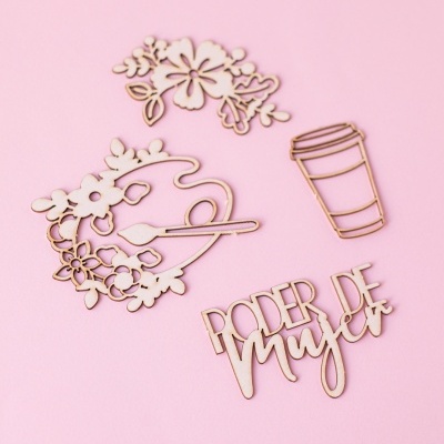 Recortes decorativos de madeira com flores, paleta, copo de café e texto em fundo rosa