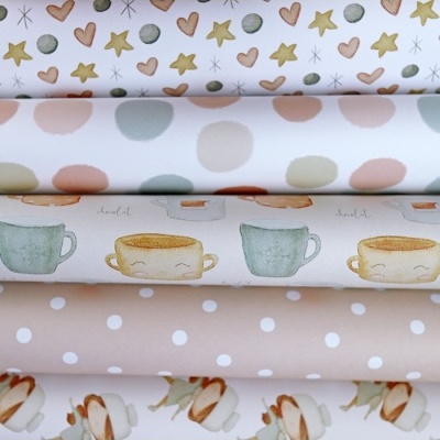 Tecido com padrões de corações, estrelas, bolas, chávenas e marshmallows dobrado em rolos