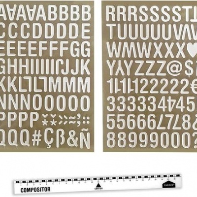 Adesivos de letras e números brancos com régua plástica branca numa superfície bege