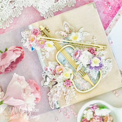 Cartão decorativo com violino dourado, flores artificiais, borboletas e rendas sobre fundo rosa