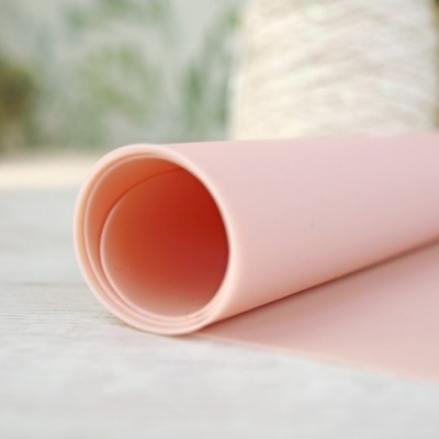 Rolo de material rosa claro e textura lisa em superfície clara