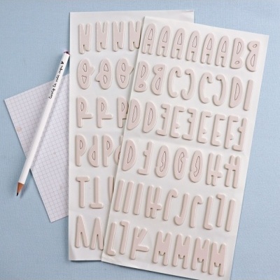 Folhas de autocolantes com letras adesivas em bege e lápis branco com texto preto