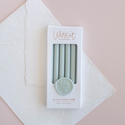 Caixa branca com velas cinza claras e selo com relevo