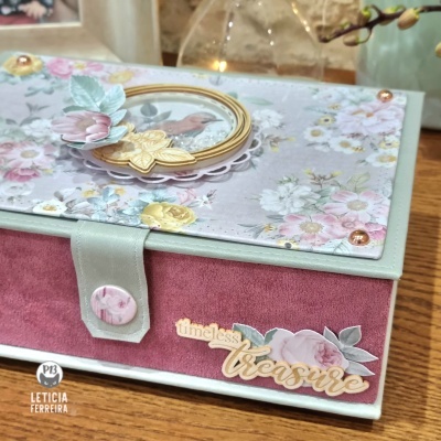 Caixa decorativa com tampa floral, fecho com botão e frase 'timeless treasure'.