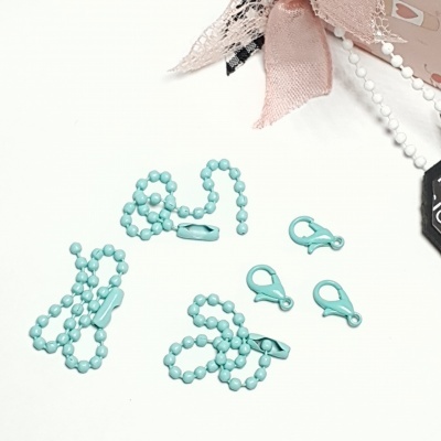 Conjunto de cadeias e fechos de mola azul turquesa sobre fundo branco com laço rosa e detalhes em plástico preto