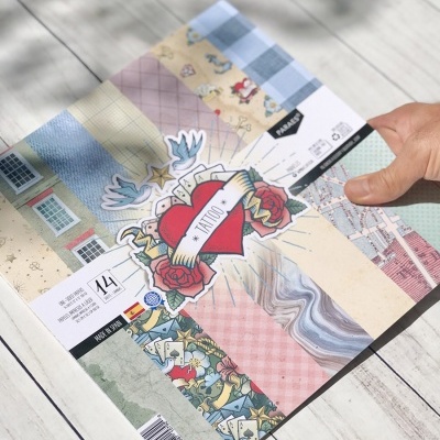 Folha de papel decorativo com várias estampas e etiqueta TATTOO sobre uma mesa branca