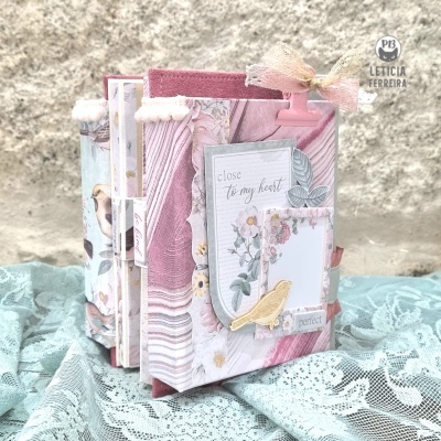 Livro artesanal decorativo com capa rosa e padrão floral com pássaros e laço de fita