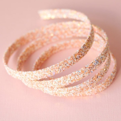 Pulseira ou bracelete espiral dourado com brilho numa superfície rosa