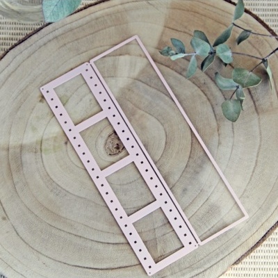 Duas molduras metálicas rosas claras sobre uma tábua de madeira circular com folhas verdes ao lado