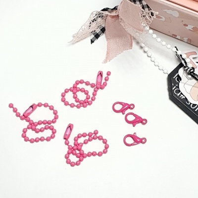 Colares rosa com contas plásticas e fechos, junto a caixa rosa decorada com fitas