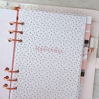 Agenda ou planner com capa branca e pontos pretos sobre superfície de madeira clara