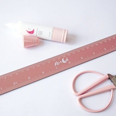 Régua rosa com marca Mia Cat, tesoura rosa e tubo branco com tampa rosa sobre fundo branco