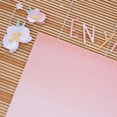 Esteira de bambu com flores de papel, letras EN cor-de-rosa e cartaz rosa com letras embutidas