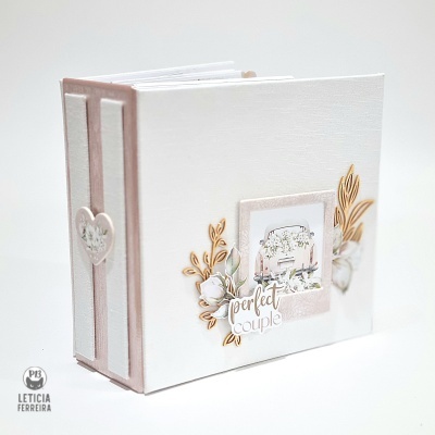 Álbum de fotos branco e rosa claro com decoração floral e frase na capa