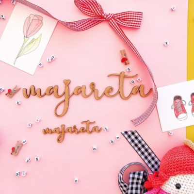 Palavras em madeira 'majareta' sobre fundo rosa com fitas, pérolas e ilustrações