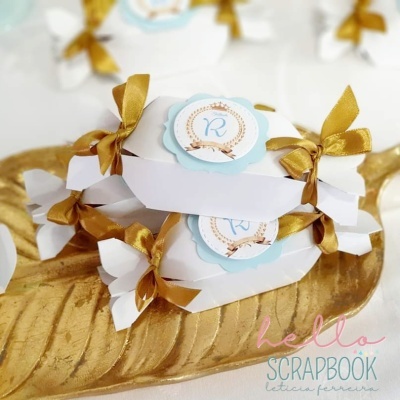 Caixas em forma de bombom com fitas douradas e etiquetas 'R' em prato dourado