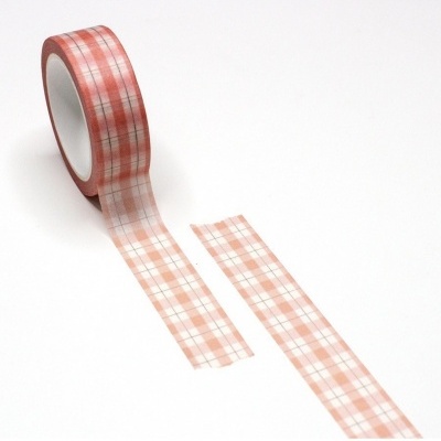 Rolo de fita adesiva com padrão vermelho e branco desenrolado sobre superfície branca