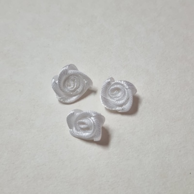 Três rosas brancas feitas de fita de cetim sobre superfície clara