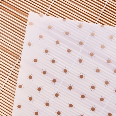 Papel transparente com padrão de círculos castanhos sobre superfície de ripas de madeira