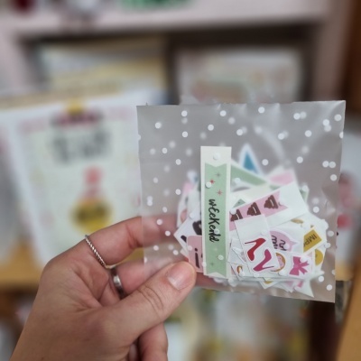 Saco transparente com bolinhas e autocolantes coloridos visto de perto em mão.