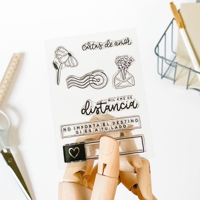 Folha de autocolantes transparentes com desenhos e texto em espanhol segurada por m e3o de manequim de madeira em mesa branca